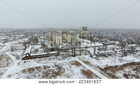 Grain Terminal In The Winter Season. Snow-covered Grain Elevator In Rural Areas. A Building For Dryi