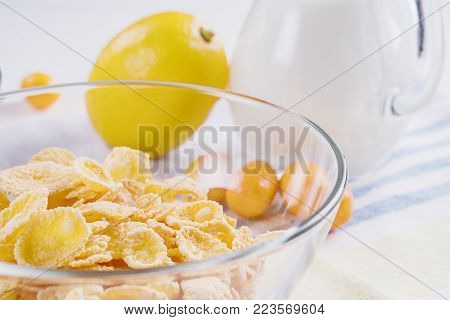 Bowl with corn flakes, jug of milk and empty bowl for prepared delicious breakfast.The concept of healthy breakfast, corn flakes with milk and fruit on wooden table, close up.