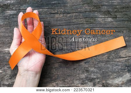 Kidney Cancer Awareness Orange Ribbon On Human Helping Hand+ Old Aged Background
