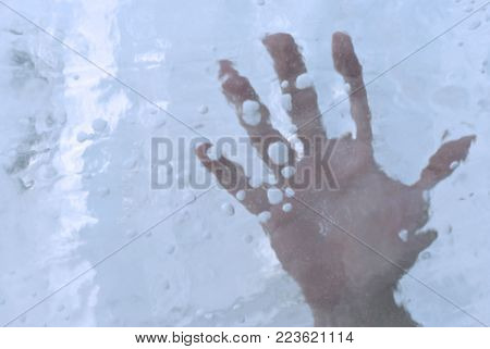 human hand in a block of ice or under ice, closeup