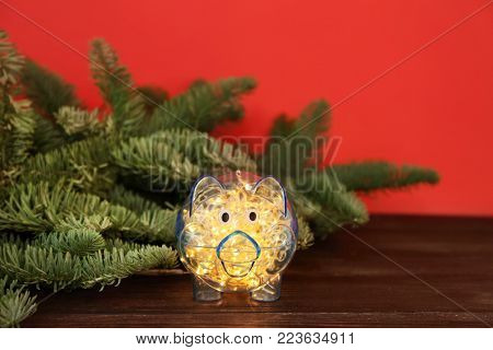 Piggy bank with Christmas garland on table