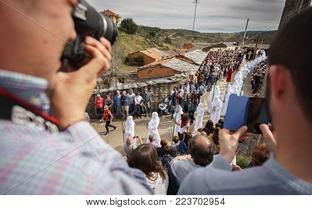 BERCIANOS, SPAIN- APRIL 3, 2015: Unidentified tourists take photos and enjoy the antique brotherhood procession with traditional clothes in Bercianos, Spain
