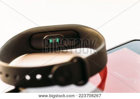 Fitness bracelet or activity tracker and smartphone with working heart rate meter and smartphone with open app, close up, selective focus