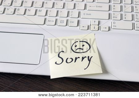 Handwritten note is on the keyboard. - Sorry. Sad smiley face drawn in black.