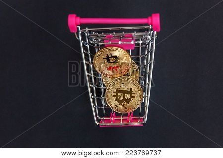 Stack of coins bitcoin in mini shopping cart toy, concept of mining. Electronic virtual money for web banking and international network payment. Symbol of crypto currency