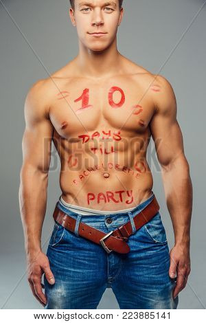 Shirtless muscular young guy with red text on his pody. Isolated on grey background.
