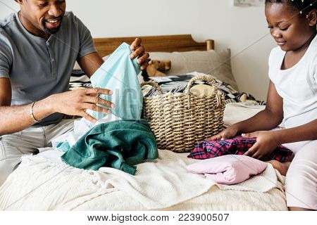 Dad and daughter folding clothes in bedroom together