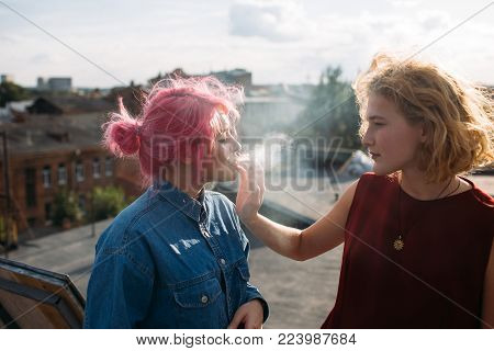 Bad influence. Girl smoking a cigarette from her friend's hand. Street teenage lifestyle. Dangers of bad associations