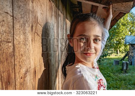 Close Up Portrait Of Beautiful Little Brunette Girl With Big Green Eyes That Looking Calmy At The Ca