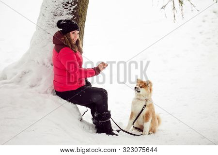 The Landlady To Train A Puppy On The Street. Girl And Fluffy Puppy For A Walk In Winter, Snowy Lands