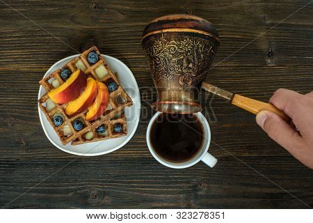 Belgian Waffles With Fruit And Berries. Male Hand Pours Coffee From A Coffee Pot. Top View