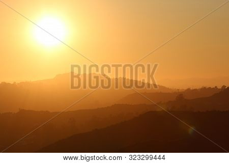 bright yellow sun by a silhouette of layers of mountains as seen in Hollywood CA
