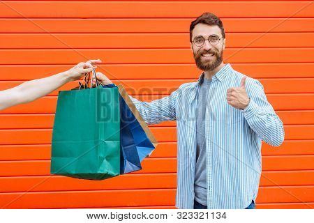 Hand Of Unrecognizable Man Holding And Giving Many Colorful Shopping Bags Excited Positive Surprised
