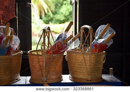 Kanchanaburi, Thailand, 09.09.2019: Handmade Braided Baskets And Traditional Thai Umbrellas In A Sma