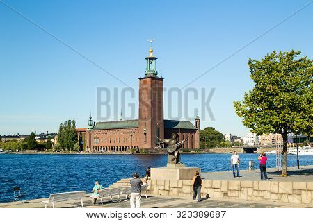Sweden, Stockholm - Circa Aug 2013: Evert Taube Monument On Background Of Stockholm City Hall. Touri