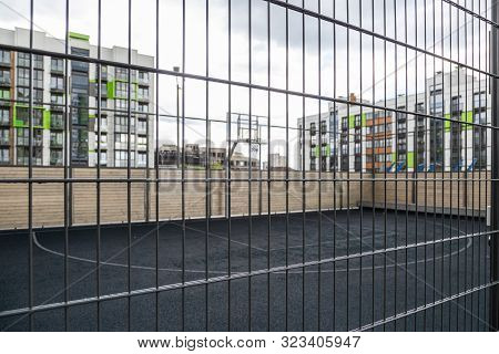 Basketball Court Behind Metal Lattice In Dormitory District. Photo With Depth Of Field
