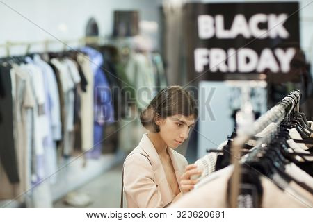 High Angle Portrait Of Young Woman Browsing Clothes On Rack While Shopping In Sale Season, Defocused
