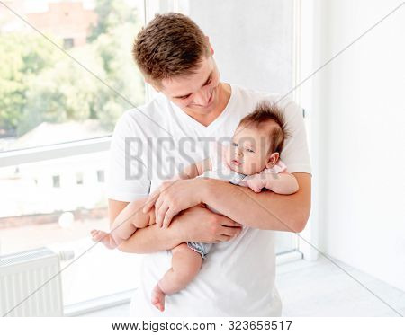 Father embracing infant near window
