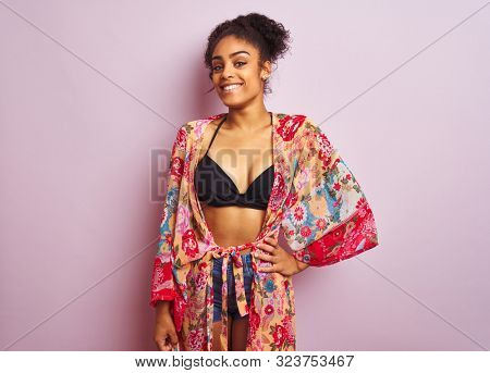 Young beautiful african american woman on vacation standing wearing bikini and colorful caftan