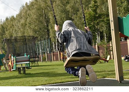 Boy Swinging On A Swing. Childr  Play In The Playground.