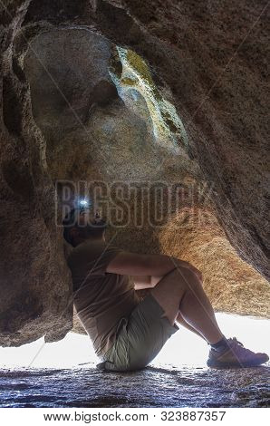 Man Observing Prehistoric Schematic Paintings Inside Granite Boulder At Natural Monumnet Of Los Barr