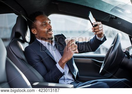 Positive Male Entrepreneur In Business Suit Having Mobile Conversation While Sitting In Car With Cup