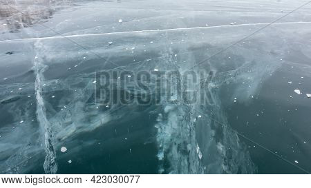 Ice Surface Close-up, Detailed. Deep Intersecting Cracks, Frozen Bubbles Are Visible On The Turquois