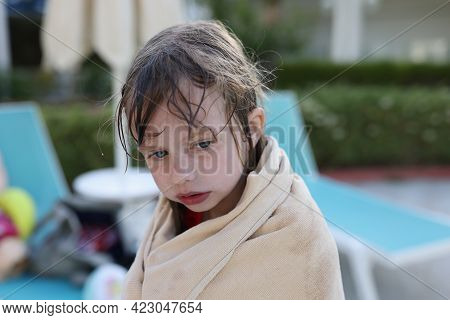 Little Frozen Girl Sits On Beach In Towel