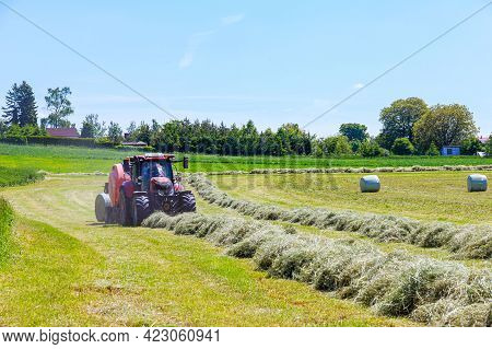 Hroubovice, Czech Republic, 4 June 2021: A Red Tractor And A Hay Baler At Work In A Rural Field In C