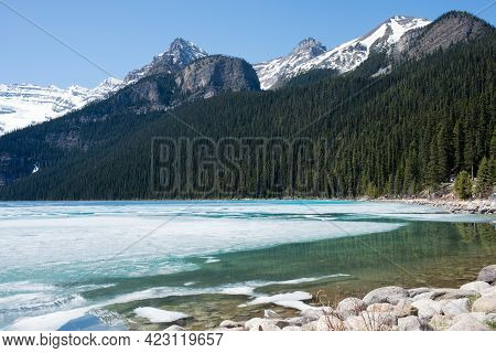 Beautiful Landscape On A Sunny Day At Frozen Lake Luise. People In The Distance Walking Near The For