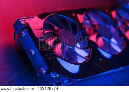 Large And Powerful Graphics Card With Three Fans With Blue Pink Light.