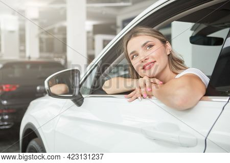 Charming Young Woman Looking Away Dreamily, Ditting In A New Automobile At Dealership