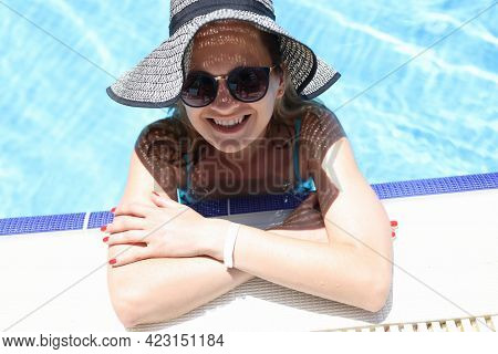 Portrait Of Smiling Woman In Hat And Sunglasses In Pool