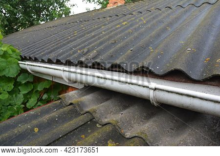 A Close-up Of An Asbestos Roof With A Plastic Roof Gutter. An Old Corrugated Asbestos Roof.