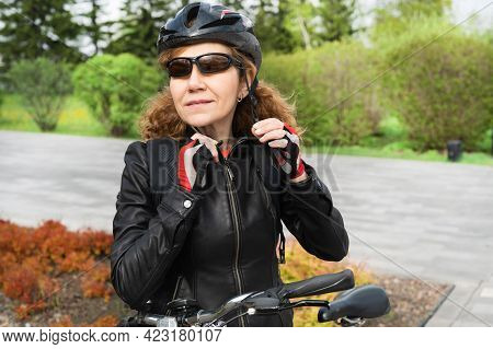 Krasnoyarsk, Russia - May 21, 2021: A Woman Puts On A Bicycle Helmet For Cycling. Sports Activities,