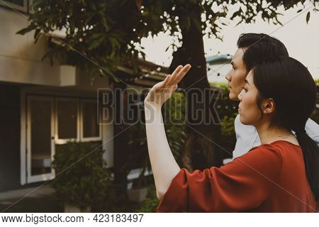 Couple Sadly Standing In Front Of The House With Nostalgia, Look At The Old House And Remember The G
