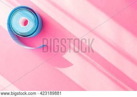 Blue Roll Of Kinesiology Tape On Pink Background With Trendy Sun Light And Shadows And Copy Space, F
