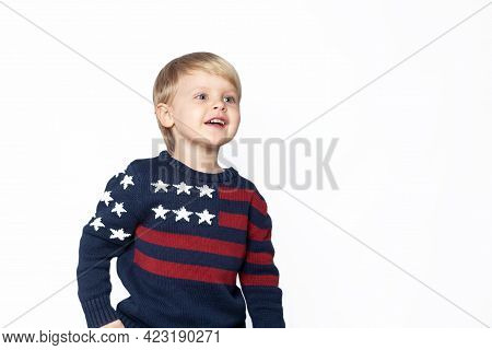 A Child In A Sweater With An American Flag Looks Out On A White Background With Copy Space.