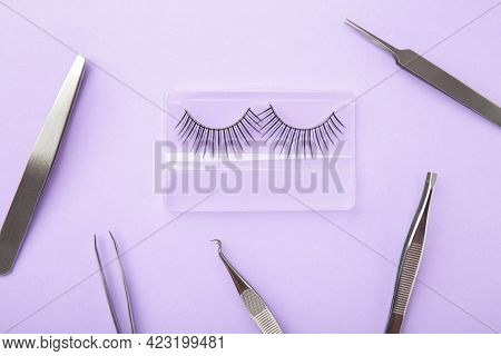 Set Of False Eyelashes Extencions On Purple Background With Tweezers. Minimalism. Top View
