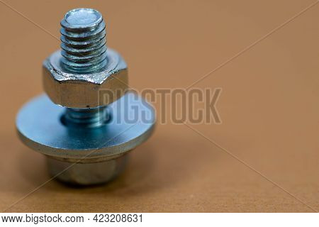 Small Bolt With Shim And Nut On Brown Background Macro Shot, Space For Text.