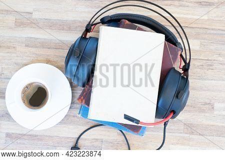 Audio Book Concept. Black Headphones With Books And Cup Of Black Fresh Coffee On Wooden Table. Top V
