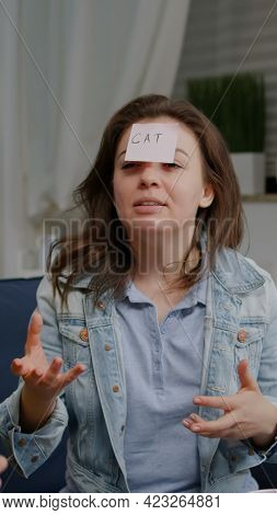 Multiethnic Friends Sitting On Sofa Late At Night Playing Guess Who Game Attaching Sticky Notes On F