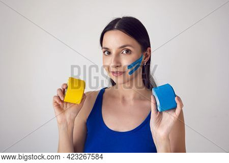 Woman Holds Two Skeins Of Kinesio Tape In Her Hand