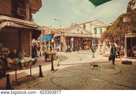 Ayvalik, Turkey: Street Life With Walking People Past Local Shops And Market On Bright Day In Ancien