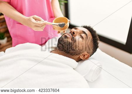 Man reciving facial treatment at beauty center.