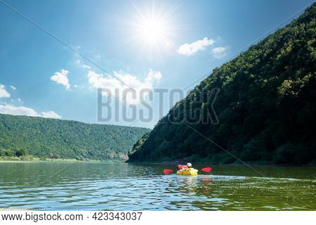 Tourist on yellow packraft rubber boat with red padle on a sunrise river. Packrafting. Active lifestile concept