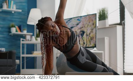 Athlete Black Woman Training On Yoga Map In Living Room Standing In Side Plank Watching Fitness Vide