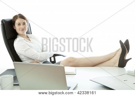 Mulher de negócios jovem com os pés na mesa e sorrindo
