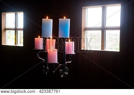 Standaard With Colored Candles In Wooden Cabin With Daylight Shinning Through The Windows
