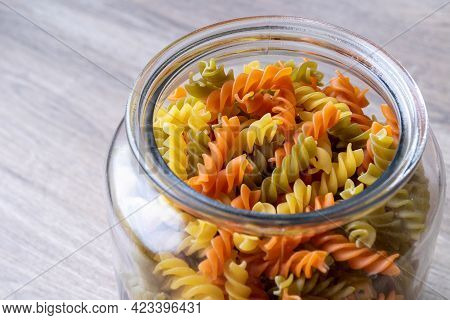 A Glass Pot, Jar Or Bowl Full Of Spirelli In Three Different Colors. The Uncooked Tricolore Italian 